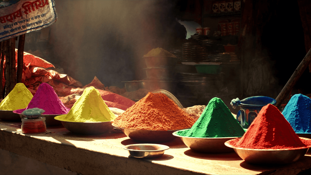 Heaped bowls of bright Holi colour powder in pink, yellow, orange, green and blue on a market stall in India