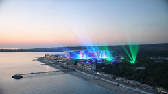 Burgas seafront and pier on the Black Sea at dusk, with stage lights beaming from an arena on the coast