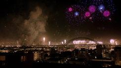 New Year's Eve fireworks bursting over a harbour city and an arch bridge at midnight